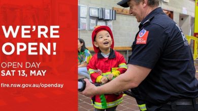An image of firefighter and a child wearing a firefighter uniform, red banner saying "We're Open!"